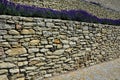 Terraces with stairs in a sloping park. stone retaining walls with light stone. blue lavender and pink roses with perennials grow Royalty Free Stock Photo
