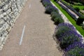 Terraces with stairs in a sloping park. stone retaining walls with light stone. blue lavender and pink roses with perennials grow Royalty Free Stock Photo