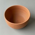 Terracotta bowl with a simple, smooth design and visible circular grooving from the Royalty Free Stock Photo