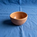 Terracotta bowl with textured patterns sits on a blue fabric surface Royalty Free Stock Photo