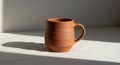 Terracotta mug with a smooth, unglazed surface placed on a light, flat surface. The m Royalty Free Stock Photo
