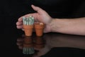 Terracotta pot with rolled up money, change and hand behind it Royalty Free Stock Photo
