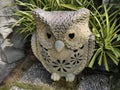 A terracotta sculpture with a cream colored pattern of an owl is set in a small garden.