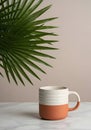 Terracotta and White Ceramic Mug with Green Palm Leaf on Marble Surface Royalty Free Stock Photo