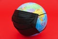 Terrestrial globe model with black surgical mask isolated on red background. Concept: Quarantined earth. Royalty Free Stock Photo