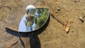 Terrestrial globe placed on an eye-shaped mirror, itself placed on the ground, in a puddle