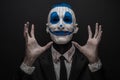 Terrible clown and Halloween theme: Crazy blue clown in black suit isolated on a dark background in the studio