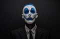 Terrible clown and Halloween theme: Crazy blue clown in black suit isolated on a dark background in the studio Royalty Free Stock Photo