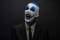 Terrible clown and Halloween theme: Crazy blue clown in black suit isolated on a dark background in the studio Royalty Free Stock Photo