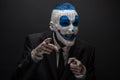 Terrible clown and Halloween theme: Crazy blue clown in black suit isolated on a dark background in the studio Royalty Free Stock Photo