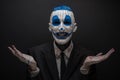 Terrible clown and Halloween theme: Crazy blue clown in black suit isolated on a dark background in the studio Royalty Free Stock Photo