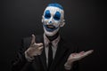 Terrible clown and Halloween theme: Crazy blue clown in black suit isolated on a dark background in the studio Royalty Free Stock Photo