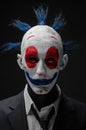 Terrible clown and Halloween theme: Crazy terrible blue clown in black suit isolated on a dark background in the studio
