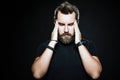 Terrible headache. Frustrated man touching head with hands and making face while standing against black background. Copy space for Royalty Free Stock Photo