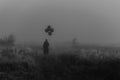 terrible man in a hooded cloak with balloons in his hand stands in a foggy field Royalty Free Stock Photo