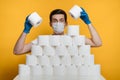 Scared young man in medical mask behind a wall of toilet paper against COVID 19 Royalty Free Stock Photo