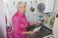 Terrified senior poor woman is checking water meter at home