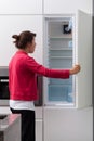 Terrified woman against the empty fridge