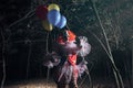 Terrifying clown with air balloons outdoors at night. Halloween party costume Royalty Free Stock Photo