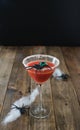 Terrifying red cocktail with spider on black background and wooden Halloween table with decoration. Vertical