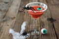 Terrifying red cocktail with spider on wooden background for Halloween with decoration. Photo vertical