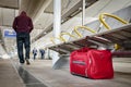 Terrorism and public safety concept with an unattended bag left under chair on platform at train station or airport and man