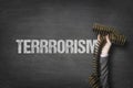 Terrorism text on blackboard with businessman hand holding ammunition