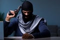 The terrorist burglar with gun working at computer Royalty Free Stock Photo