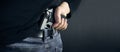 Terrorist thief man holding gun in his hand. Hidden gun. Isolated on dark background. copy space. Royalty Free Stock Photo