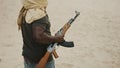 Terrorist walking on sandy terrain with an AK 74 in his hands.