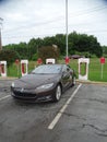 A Tesla car battery`s recharging station with a Tesla car parked at the charging ba