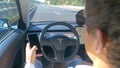 CLOSE UP Commuter sitting in a Tesla car checks phone while driving down highway
