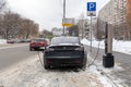 The Tesla Model 3 electric car is charged at a municipal charging station in winter. Using the electric car in freezing Royalty Free Stock Photo