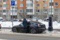 Tesla Model 3 electric car charging in a street parking lot in winter. Using the electric car in freezing temperatures