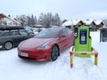 Tesla red passenger electric car replenishes battery at charging station in Levi ski resort, winter day, Lapland, alternative Royalty Free Stock Photo