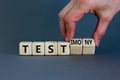 Test or testimony symbol. Businessman turns wooden cubes and changes the word `test` to `testimony`. Beautiful grey background