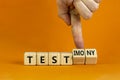 Test or testimony symbol. Businessman turns wooden cubes and changes the word `test` to `testimony`. Beautiful orange backgrou