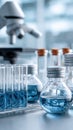 Test tubes with blue liquid stand next to a modern microscope on a table in a laboratory setting with a simple background Royalty Free Stock Photo
