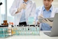 Test tubes with chemical liquid on the table over blurred two scientist working together Royalty Free Stock Photo