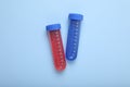 Test tubes with colorful liquids on light blue background, flat lay. Kids chemical experiment set