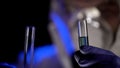 Test tubes in hands of scientist closeup, mixing chemical substances, analysis