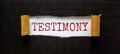 Testimony symbol. The word `Testimony` appearing behind torn black paper. Beautiful black background. Business, testimony concep