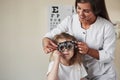 Testing what`s better for his eyes. Doctor checking little girl sight and tuning the phoropter