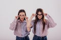 Tests new glasses. Two sisters twins standing and posing in the studio with white background Royalty Free Stock Photo