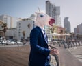 Unusual manager in funny mask and suit stands on city promenade Royalty Free Stock Photo