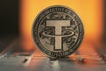 Tether USDT Crypto coin placed on laptop keyboard and lit with orange light from behind.