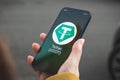 Tether USDT cryptocurrency symbol, logo. Business and financial concept. Hand with smartphone, screen with crypto icon