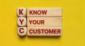 Text text acronym KYC with know your customer written on wooden blocks stacked on a yellow background