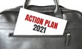 Text ACTION PLAN 2021 writing on white paper sheet in the black business bag. Business concept