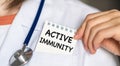 Text Active Immunity on a notebook in the hands of a doctor against the background of a table with medicaments. Medical concept